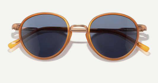 Round sunglasses with gold frame and dark lenses on a white background