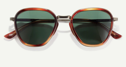 Sunglasses with tortoiseshell frame and green lenses on a white background