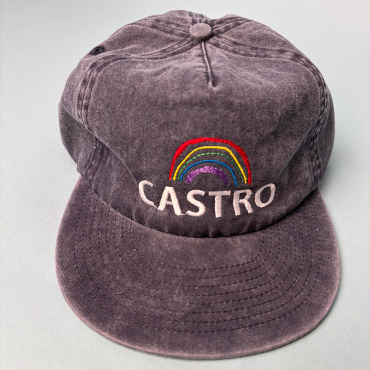 A washed dark gray baseball cap featuring an embroidered multicolor rainbow and the name 'CASTRO' in white text on the side, displayed on a light gray background.