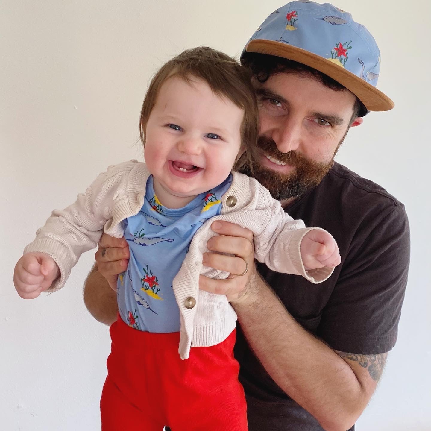 Jamai Lowell holding one of his daughters, both wearing one of our dad and baby matching outfits.