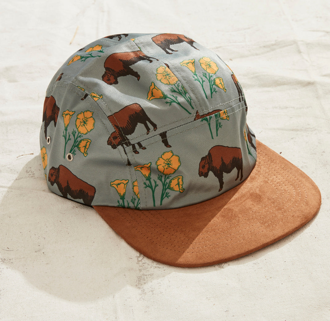 Five panel hat with bison and poppy pattern and a brown suede brim.