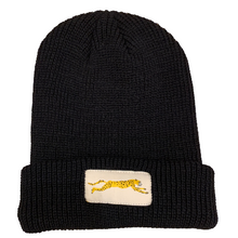Black beanie hat with a light-beige rectangular patch stitched on the front. Printed on the patch is a cheetah in mid-run.